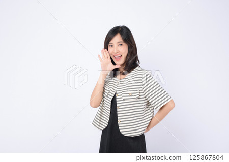 Southeast asian woman smiling and advertising with cheerful expression wearing striped jacket and black dress on white background 125867804