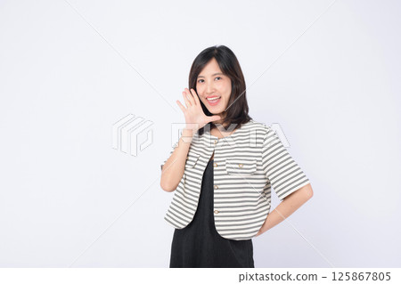 Cheerful southeast asian woman in striped jacket smiling and advertising with hand gesture on white background for marketing use Cheerful southeast asian woman in striped jacket smiling and advertising with hand gesture on white background for marketing use 125867805