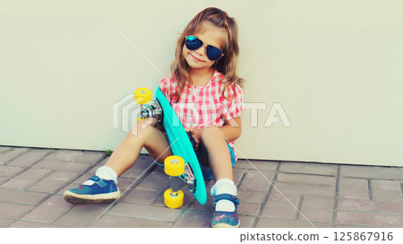 Stylish little girl child posing with skateboard on city street 125867916