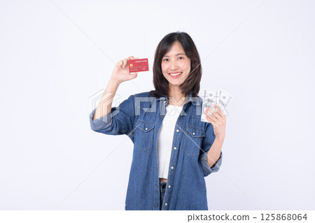 Southeast Asian woman smiling and holding credit card and cash money showing internet banking and mobile payment application concept with happy expression 125868064
