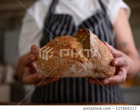 Artisan Sourdough Bread in Hand - Fresh from the Oven. Artisan Sourdough Bread in Hand - Fresh from the Oven. 125868317