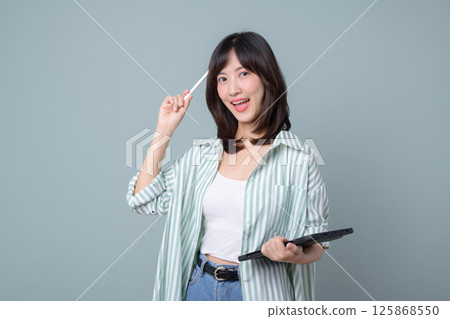 Creative southeast asian woman small business owner holding laptop and pen smiling confidently representing retail startup and online store industry success Creative southeast asian woman small business owner holding laptop and pen smiling confidently representing retail startup and online store industry success 125868550