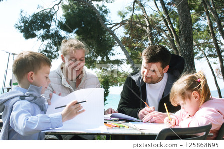 happy family doing homework outside in cafe, lifestyle people 125868695
