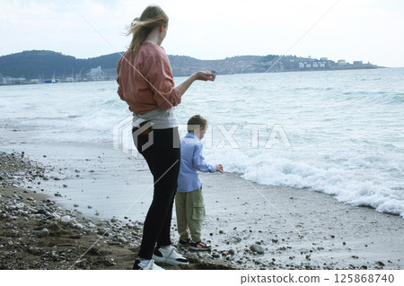 young mother playing with her son with rock on beach, happy lifestyle family young mother playing with her son with rock on beach, happy lifestyle family 125868740