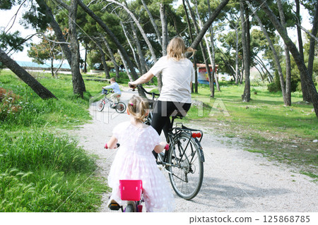 cute mother with children riding on bicycles on sea side, lifestyle people concept 125868785