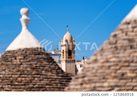 Trulli rooftops with bell tower in the background 125868916