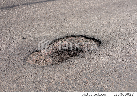 A deep pothole appears on a city street, creating possible risks for vehicles and pedestrians passing through the area 125869028