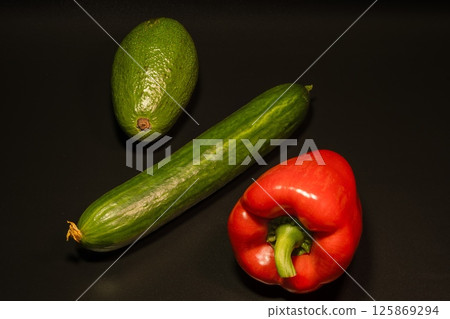 Avocado, cucumber, pepper on a black background 125869294
