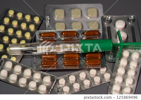 Tablets on a background with a thermometer Tablets on a background with a thermometer 125869496