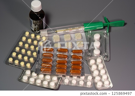 Tablets on a background with a thermometer Tablets on a background with a thermometer 125869497