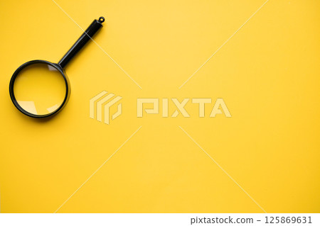 Top view of magnifying glass on yellow background, space for text. Search concept 125869631
