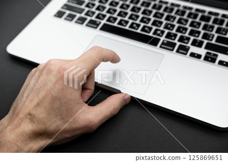 Man's hand and gray laptop computer. Closeup of man's hands using modern laptop. Selective focus on hand Man's hand and gray laptop computer. Closeup of man's hands using modern laptop. Selective focus on hand 125869651