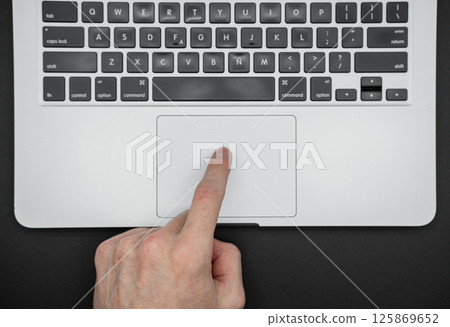 A man uses a laptop. The finger points to the touchpad. Close up top view A man uses a laptop. The finger points to the touchpad. Close up top view 125869652