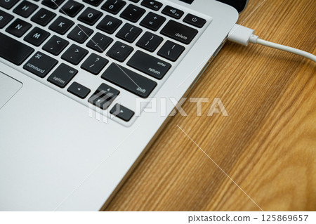 A modern laptop computer stands on a wooden table 125869657