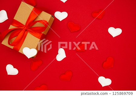 Valentine's Day background. Gift box of kraft paper with red bow on red background with hearts. Place for text, banner. 125869709