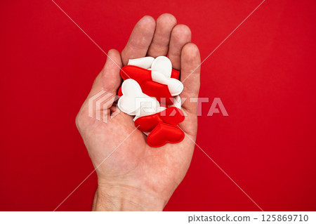 Banner with hands holding red and white hearts on red textured background. Concept of health care, love or Valentine's day Banner with hands holding red and white hearts on red textured background. Concept of health care, love or Valentine's day 125869710