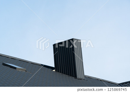 Black roofing of metal profile wavy shape. Roof with a skylight and a chimney 125869745