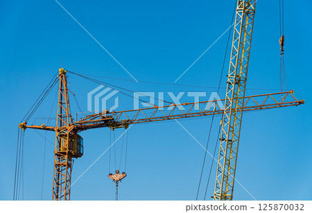 Two yellows construction cranes. Modern construction. Housing construction 125870032