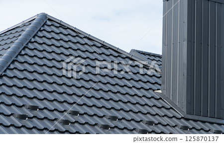 A fragment of the roof made of metal roof tiles. Modern roof made of metal A fragment of the roof made of metal roof tiles. Modern roof made of metal 125870137