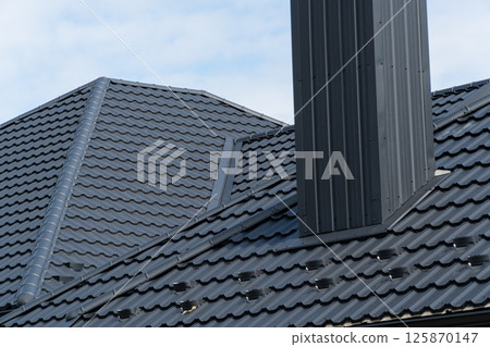 Black metal profile roof installed on a modern house. Modern types of roofing materials 125870147