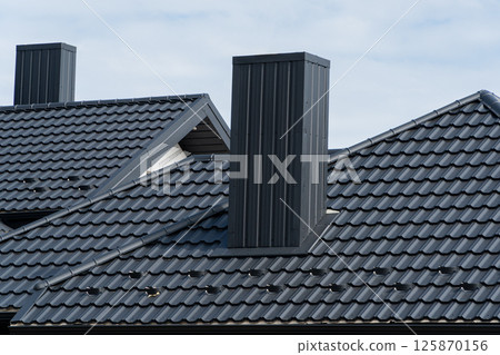 Metal modern roof and chimney on the roof of the house. Beautiful clean roof made of metal profile Metal modern roof and chimney on the roof of the house. Beautiful clean roof made of metal profile 125870156