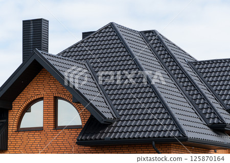 Roof of a new home. Roof covering with steel tiles. Modern roof made of metal Roof of a new home. Roof covering with steel tiles. Modern roof made of metal 125870164