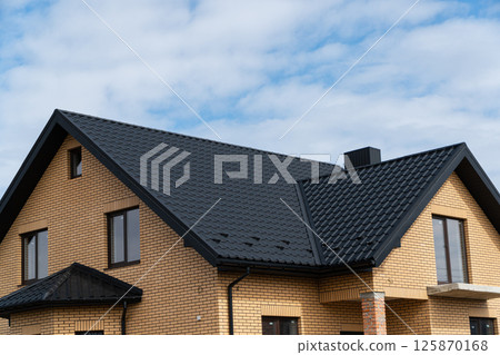 New brick house. The modern house with plastic windows and a black roof of corrugated sheet. Metal roofing 125870168