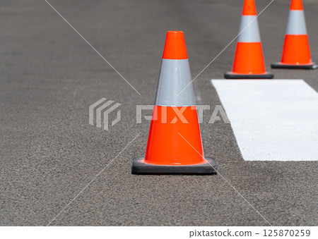 Road traffic cones standing on street on gray asphalt during road construction works. Traffic cones for road works Road traffic cones standing on street on gray asphalt during road construction works. Traffic cones for road works 125870259