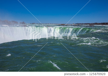 Witness the powerful Niagara Falls located in Ontario, Canada, showcasing the breathtaking waterfall cascading into the river below. 125870920