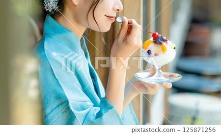 A Japanese woman in a yukata eating shaved ice on the veranda 125871256