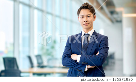 Smiling male businessman with arms folded Smiling male businessman with arms folded 125871980