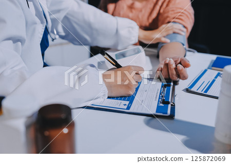 Nurse measuring blood pressure of elderly woman at table, closeup. Assisting senior generation 125872069