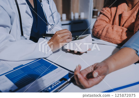 Nurse measuring blood pressure of elderly woman at table, closeup. Assisting senior generation Nurse measuring blood pressure of elderly woman at table, closeup. Assisting senior generation 125872075