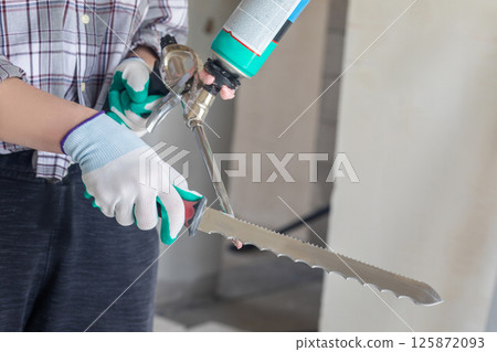 Cleaning a foam gun with a serrated knife . 125872093