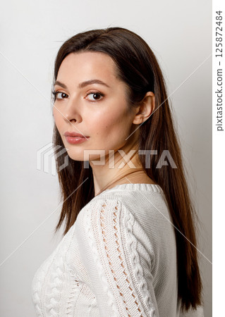Beautiful woman in white knitted sweater posing indoors 125872484