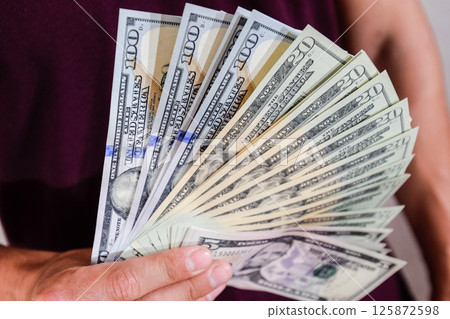 dollars are held by fan by a man in his hand. Us dollar. 125872598