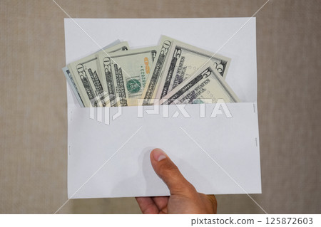 Money in white envelope in the hands of a man. Dollars, a wad of dollars. Money in white envelope in the hands of a man. Dollars, a wad of dollars. 125872603
