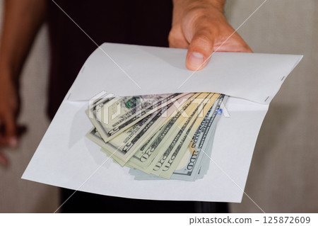Money in white envelope in the hands of a man. Dollars, a wad of dollars. Money in white envelope in the hands of a man. Dollars, a wad of dollars. 125872609