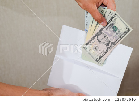 Money in white envelope in the hands of a man. Dollars, a wad of dollars. Money in white envelope in the hands of a man. Dollars, a wad of dollars. 125872610
