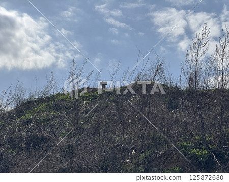 Cross on a windswept hill under a bright spring sky 125872680