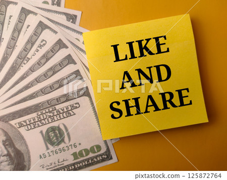 Banknotes and sticky note with the word LIKE AND SHARE on a yellow background. 125872764