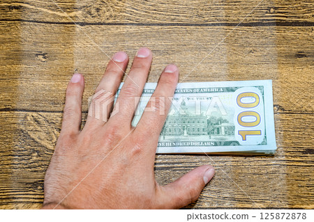 The man at table holds bills. Dollars in hand. 125872878