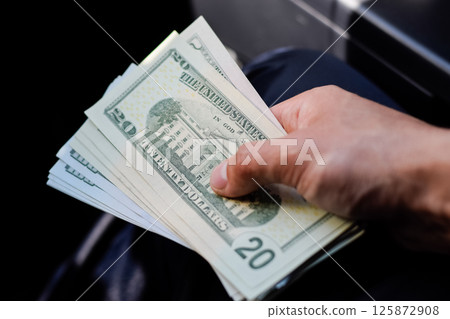 man hands over money in a car. A wad of dollars in his hand. 125872908