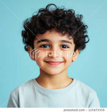 A cheerful, smiling Arabic boy, 8-10 years old, stands on a pastel plain background, embodying a bright and fresh style perfect for advertising photography 125873359