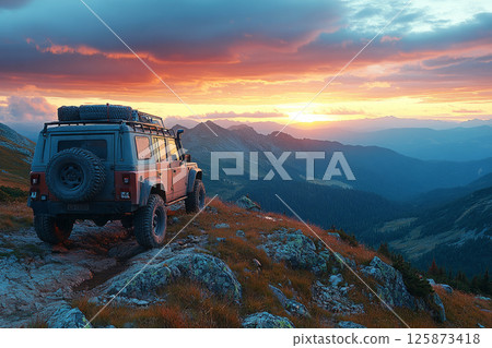Rugged 4x4 stands on a high ridge at dawn, golden sun rising over vast peaks in a bold and wild overland escape 125873418