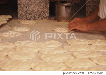 Baker shaping traditional bread on a work surface in a cozy kitchen Baker shaping traditional bread on a work surface in a cozy kitchen 125873504