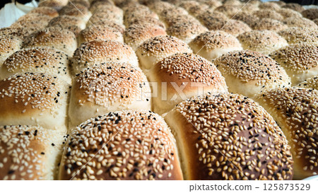Freshly baked sesame rolls arranged in a cozy bakery Freshly baked sesame rolls arranged in a cozy bakery 125873529