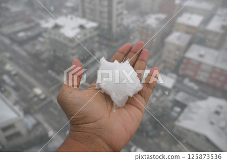 Snowball in palm during urban snowstorm on a winter day 125873536