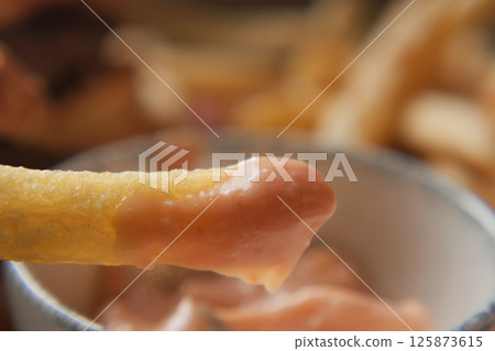 Delicious fried potato stick dipped in creamy sauce at a diner 125873615