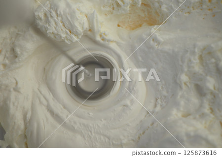 Cream being whipped to perfection in a mixing bowl during preparation Cream being whipped to perfection in a mixing bowl during preparation 125873616